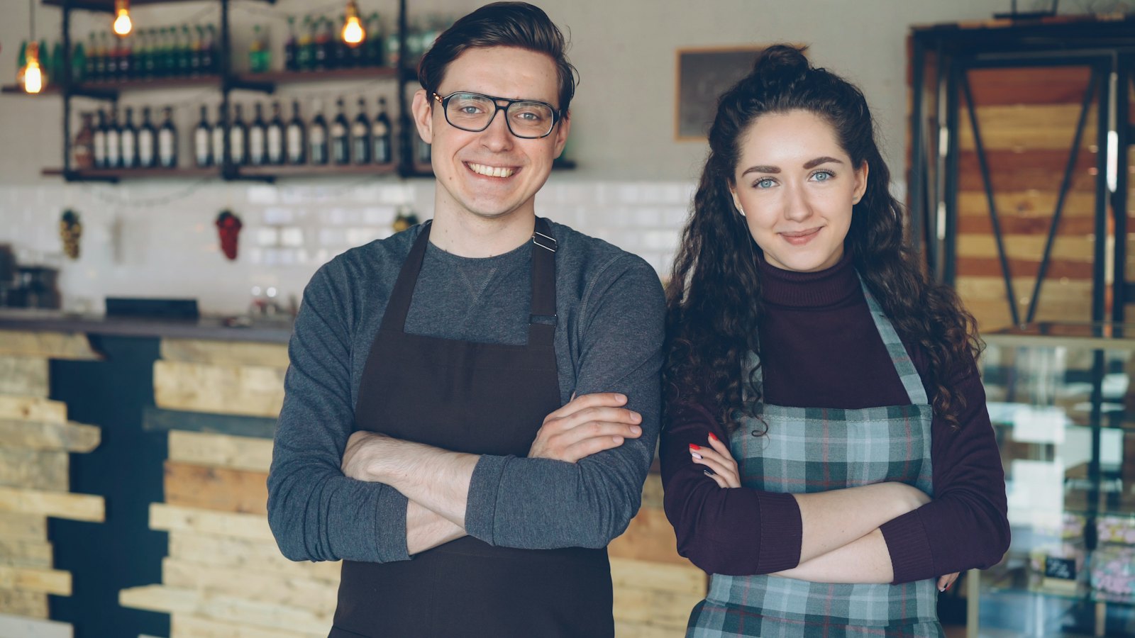 Dois sócios de um pequeno café sorrindo atrás do balcão